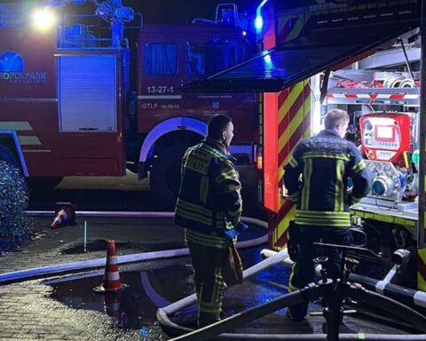 Großbrand auf Flugplatz: Zerstörte Gebäude, Feuerwehr im Einsatz, Löschfahrzeuge bei der Wasserförderung.