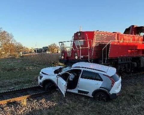 Unfall zwischen PKW und Güterzug am Bahnübergang, Rettungsdienst und Polizei vor Ort.