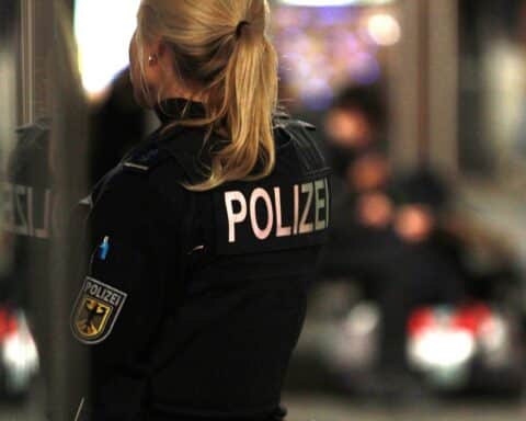 Polizeikontrolle mit Beamten, Fahrzeugen und alkoholischen Getränken symbolisiert Gefahren im Straßenverkehr.