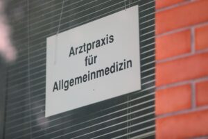 Arztpraxis mit Patienten; Diskussion über neue Gebühren für Arztbesuche in Deutschland.