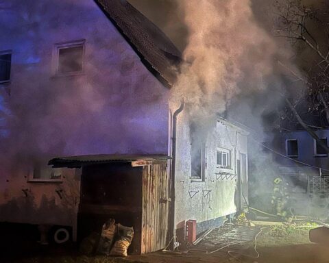 Küchenbrand in Neuss: Feuerwehr im Einsatz, Bewohner evakuiert, Flammen aus Fenster.