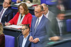Friedrich Merz in Berlin, umgeben von Immobilienvertretern und Mieterschutzaktivisten, symbolisierendes Ungleichgewicht.