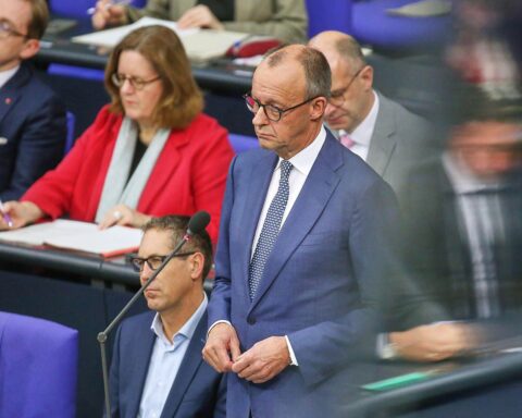 Friedrich Merz in Berlin, umgeben von Immobilienvertretern und Mieterschutzaktivisten, symbolisierendes Ungleichgewicht.