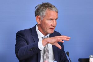 Björn Höcke spricht öffentlich, umgeben von symbolischen Elementen der politischen Auseinandersetzung.