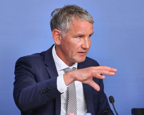 Björn Höcke spricht öffentlich, umgeben von symbolischen Elementen der politischen Auseinandersetzung.