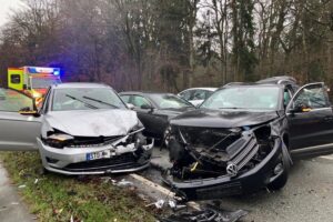 Schwerer Verkehrsunfall auf Bundesstraße: beschädigte Autos, Rettungsdienste, gesperrte Fahrbahn, Verkehrsbehinderungen.