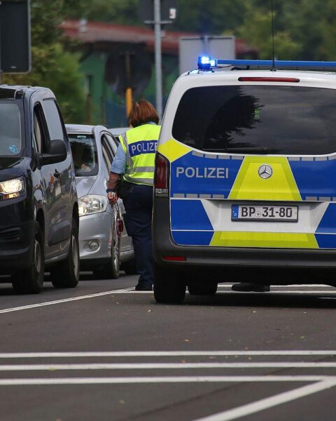 Binnengrenzkontrolle in Deutschland mit Beamten und Reisenden in einer urbanen Umgebung.