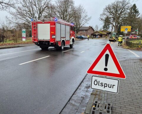 Ölspur auf Straße, Feuerwehr bei der Beseitigung, Warnschilder und Sandwälle sichtbar.