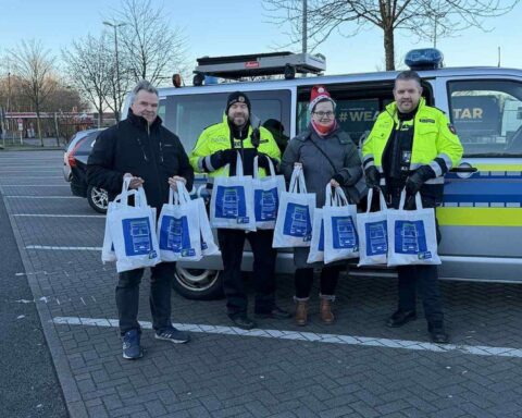 Polizisten überreichen Geschenktüten an Lkw-Fahrer an Weihnachten auf Autobahnrastplätzen.