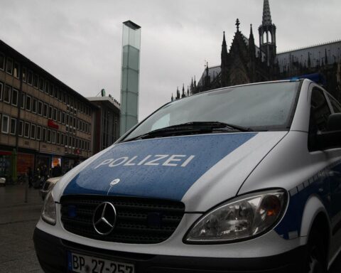 Polizeiauto vor Kölner Dom, hält Fahrer nach illegalem Straßenrennen mit VW Golf an.