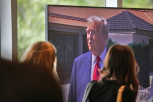 Donald Trump, umgeben von politischen Symbolen, während er Europa und Migration kritisiert.