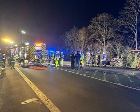Zwei vereiste Autos an Unfallstelle, Feuerwehr im Einsatz, verletzte Personen werden gerettet.