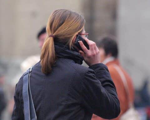 Frau telefoniert lächelnd und wünscht Neujahrsgrüße – symbolisiert Kommunikation und Tradition.