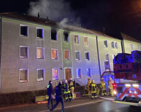 Feuerwehr bei Wohnungsbrand: Einsatzkräfte retten zwei Menschen über Drehleiter, Gebäude in Flammen.