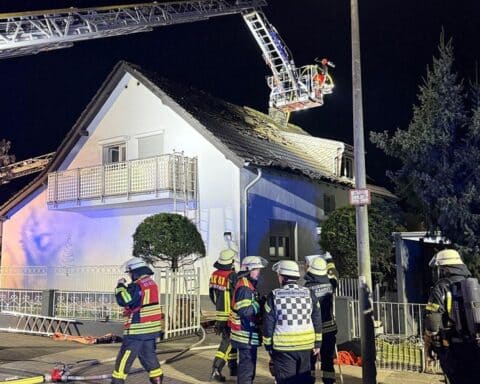 Feuerwehr im Einsatz mit Drehleitern bei nächtlichem Brand in Mehrfamilienhaus.