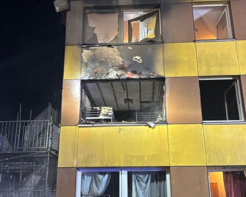 Feuerwehr im Einsatz bei Zimmerbrand in Unterbringungseinrichtung, evakuierte Bewohner, starke Rauchentwicklung.