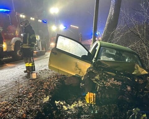 Verkehrsunfall mit Feuerwehranwe­senheit, gesperrte Straße, beschädigtes Fahrzeug und Leitplanke.