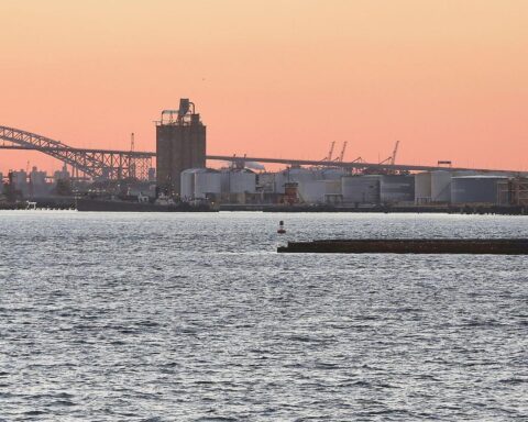 Industrieanlagen im Hafen von New York mit Öltanks, symbolisieren Energieimport und geopolitische Beziehungen.