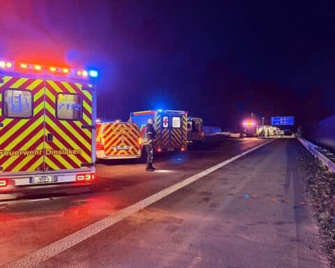 Rettungsfahrzeuge und Feuerwehrkräfte an der Unfallstelle auf der Autobahn, Einsatz in der Nacht.