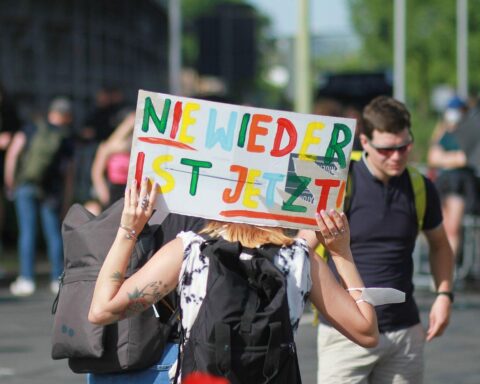 Protestierende Menschen halten Plakate gegen Rechtsextremismus und für Demokratie und Vielfalt hoch.