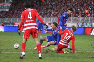 Dramatische Fußballszene: Union Berlin und Mainz 05 kämpfen um den Ball, Zuschauer jubeln.