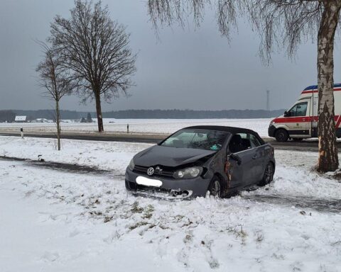 Unfallfahrzeug nach Kollision mit Baum auf Bundesstraße mit Feuerwehr und Rettungsdienst im Einsatz.