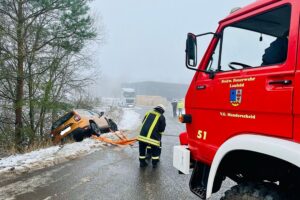 Ein PKW rutscht auf glatter Straße von der Fahrbahn, Feuerwehr sichert und bergt ihn.