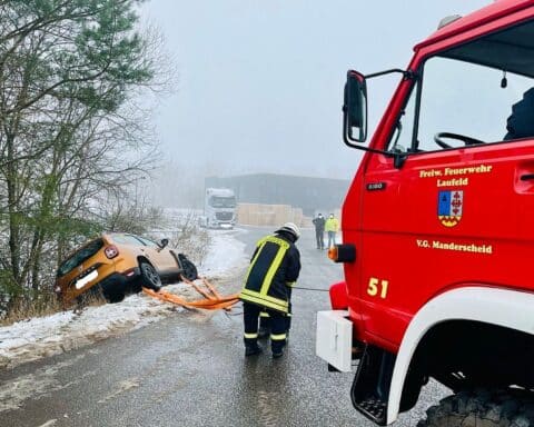 Ein PKW rutscht auf glatter Straße von der Fahrbahn, Feuerwehr sichert und bergt ihn.