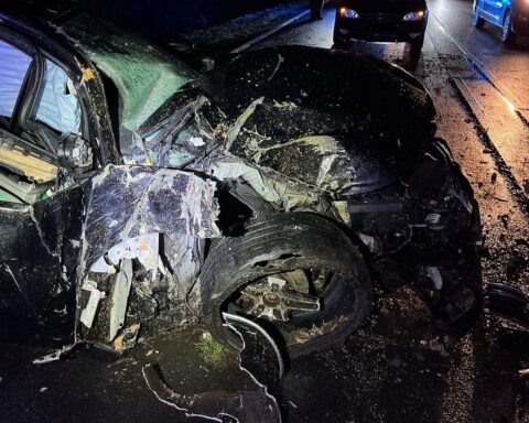 Ein stark beschädigter BMW nach einem Unfall auf der Bundesstraße, Umgebung sichtbar.