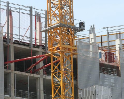 Baustelle mit Handwerkern, Materialien und Baustellenfahrzeugen, die den Neubau von Wohngebäuden symbolisieren.