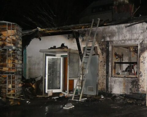 Abgebrannte Lagerhalle mit sichtbaren Brandschäden; Feuerwehr und Polizei bei der Brandermittlung.