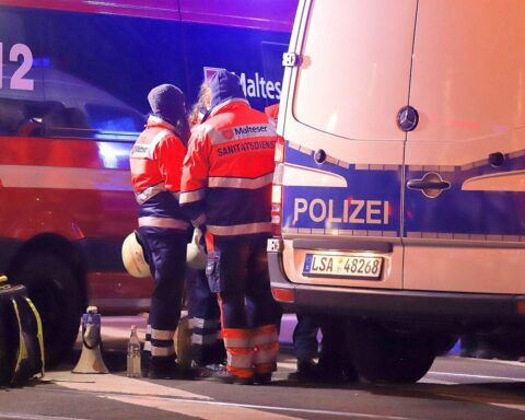 Brennendes Gebäude, Feuerwehr im Einsatz, Rettungskräfte, beschädigte Fahrzeuge, Einsatzkräfte am Ort.
