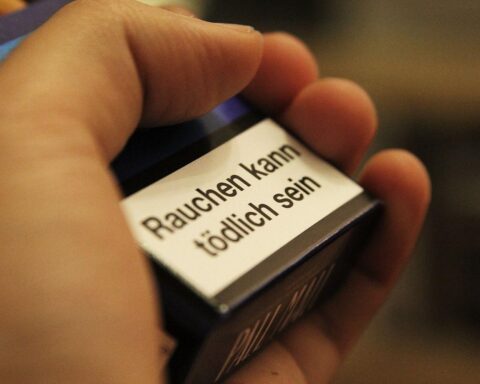 Raucherwarnung auf Zigarettenschachtel, Symbol für gesundheitliche Risiken und Diskussion über Tabaksteuer.