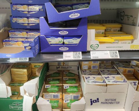 Butterpreisschilder in Supermarkt, verdeutlicht Preiskampf und Auswirkungen auf heimische Landwirtschaft.