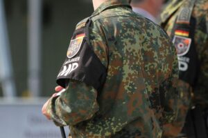 Bild zeigt Soldaten in Uniform, Militärtechnik, Drohnen und eine strategische Militärkarte.
