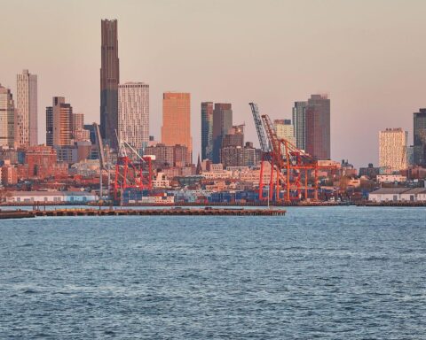 Industriehafen mit Kränen, Schiffsverkehr, New York, symbolisiert Handelsbeziehungen und Zollpolitik zwischen EU und USA.