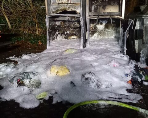 Brand zerstörte Altkleidercontainer, Feuerwehr löscht, Polizei vor Ort, Ursache unklar.