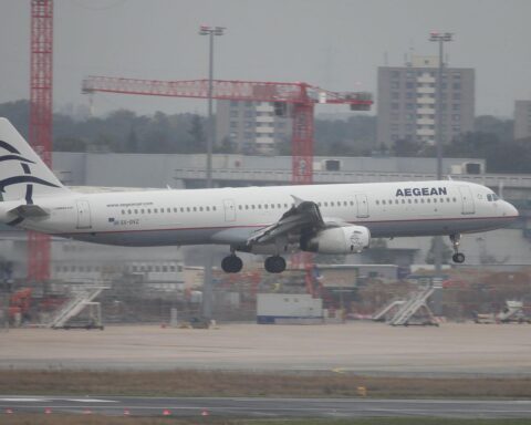 Flughafen mit gestrandeten Reisenden und Aegean Airlines Flugzeug, während Flugverkehr gestört ist.