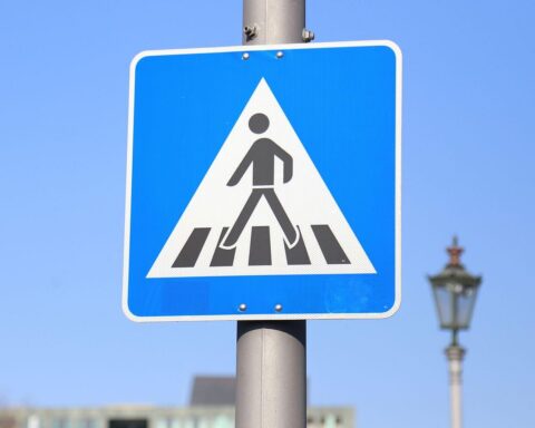 Unfallort: Zebrastreifen in Bottrop mit Fußgänger und Auto, Polizei und Rettungswagen vorbeifahrend.