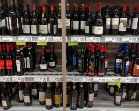 Ein Glas Rotwein auf einem Tisch, umgeben von Obst und Kampagnenmaterial für "Dry January".