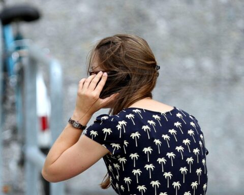 Junge Frau betrachtet Smartphone, symbolisiert Einsparungen beim separaten Kauf von Geräten und Tarifen.