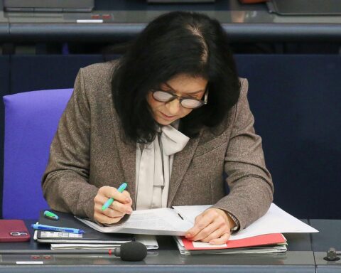 Ein Bild von Katherina Reiche, umgeben von politischen Symbolen und Kontroversen.