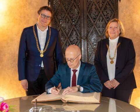 Peter Tschentscher trägt sich ins Goldene Buch Würzburgs ein, umgeben von Stadtoberhäuptern.