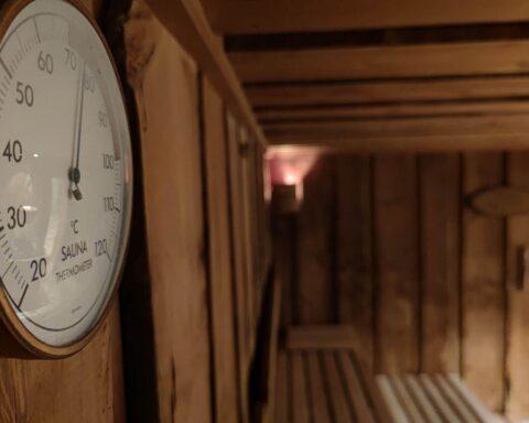 Eine öffentliche Sauna mit Menschen, die sich entspannen, während ein Smartphone verdeckt gehalten wird.