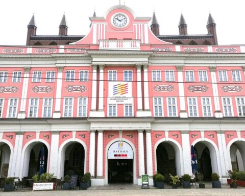 Rathaus von Rostock vor bedrohlichen Sturmfluten, symbolisiert Klimafolgen und Risiken für die Stadt.