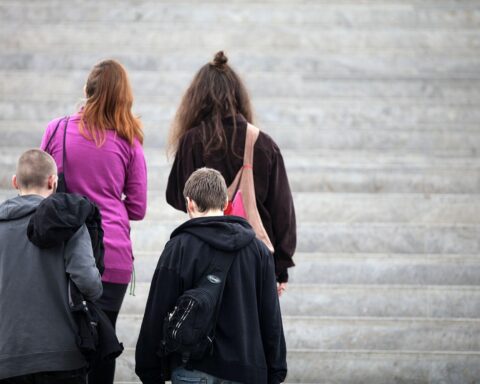 Vier junge Leute auf einer Treppe symbolisieren den sozialen Zusammenhalt in der Gesellschaft.