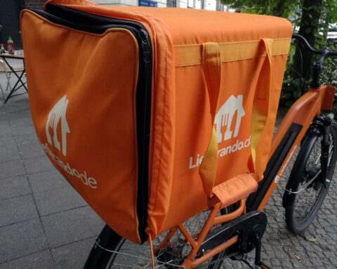Ein Lieferando-Fahrrad vor urbaner Kulisse, symbolisiert die Diskussion um Arbeitsbedingungen der Lieferanten.