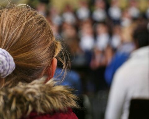 Kinder schreiben aufmerksam an Tischen, umgeben von Schulmaterial, die Wichtigkeit korrekter Rechtschreibung diskutierend.