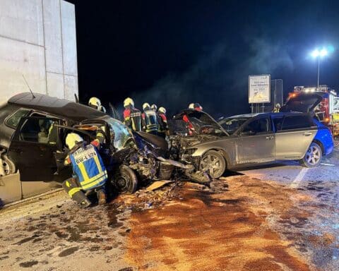 Schwerer Verkehrsunfall: Zwei beschädigte Autos, Feuerwehr im Einsatz, eingeklemmte Person wird gerettet.
