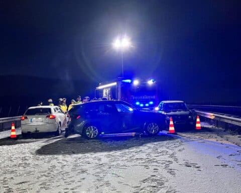 Schneebedeckte Autobahn mit Unfallfahrzeugen und Rettungskräften, zeigt winterliche Verkehrsgefahr.